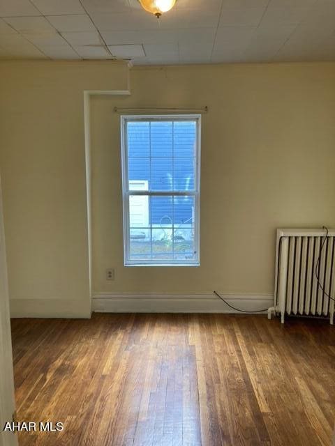 unfurnished room with radiator heating unit and hardwood / wood-style flooring