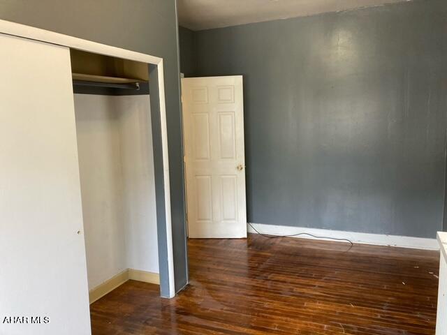 unfurnished bedroom featuring dark hardwood / wood-style floors and a closet