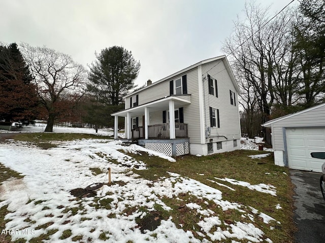 view of snow covered exterior with covered porch, an outdoor structure, and a garage