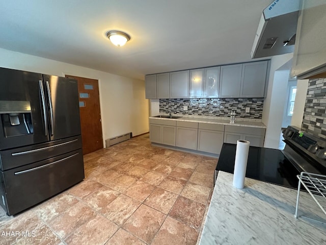 kitchen with gray cabinetry, ventilation hood, stainless steel refrigerator with ice dispenser, decorative backsplash, and baseboard heating