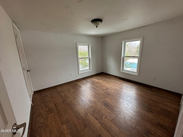 empty room featuring a wealth of natural light and dark wood-type flooring