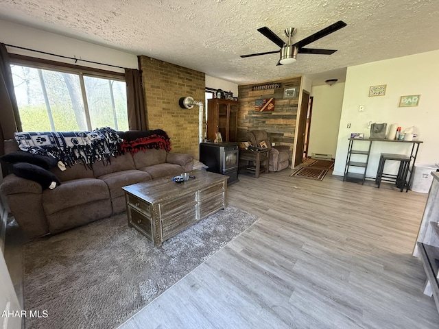 229 Celtic Ln, Altoona, PA 16601 - living area with a ceiling fan, a textured ceiling, a wood stove, wood finished floors, and a baseboard radiator