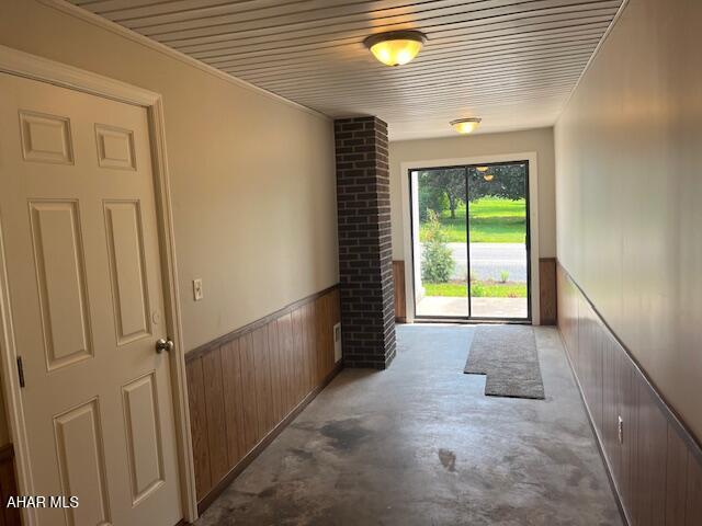 208 W 5th Ave, Everett, PA 15537 - doorway to outside featuring wainscoting, unfinished concrete floors, and wood walls