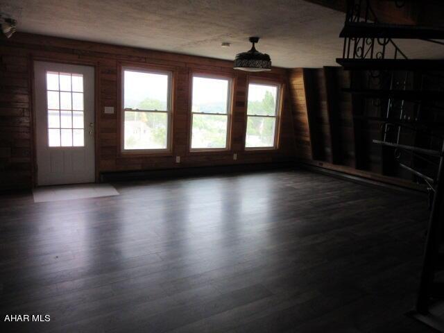 empty room with wooden walls and dark wood-type flooring