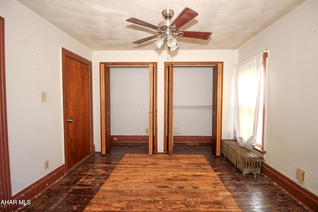 unfurnished bedroom with radiator, ceiling fan, and dark wood-type flooring