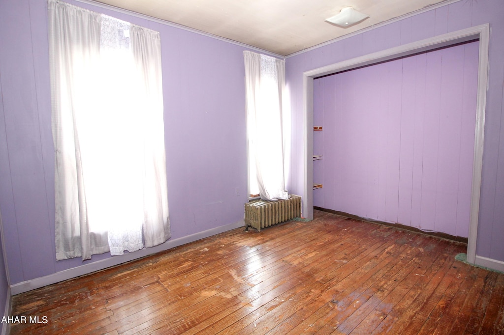 spare room featuring wood-type flooring and radiator heating unit