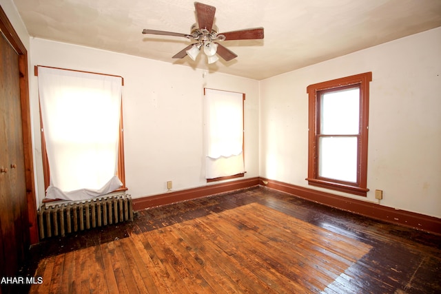 spare room with radiator, dark wood-type flooring, and ceiling fan