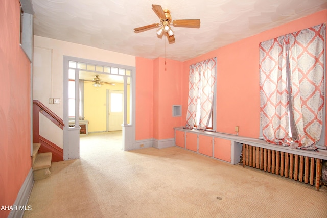 spare room with ceiling fan, radiator heating unit, and light colored carpet