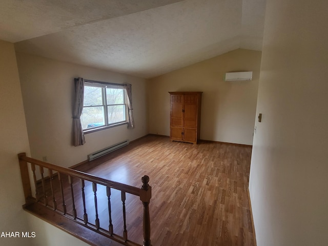 interior space with a wall mounted air conditioner, vaulted ceiling, light hardwood / wood-style flooring, a textured ceiling, and a baseboard radiator