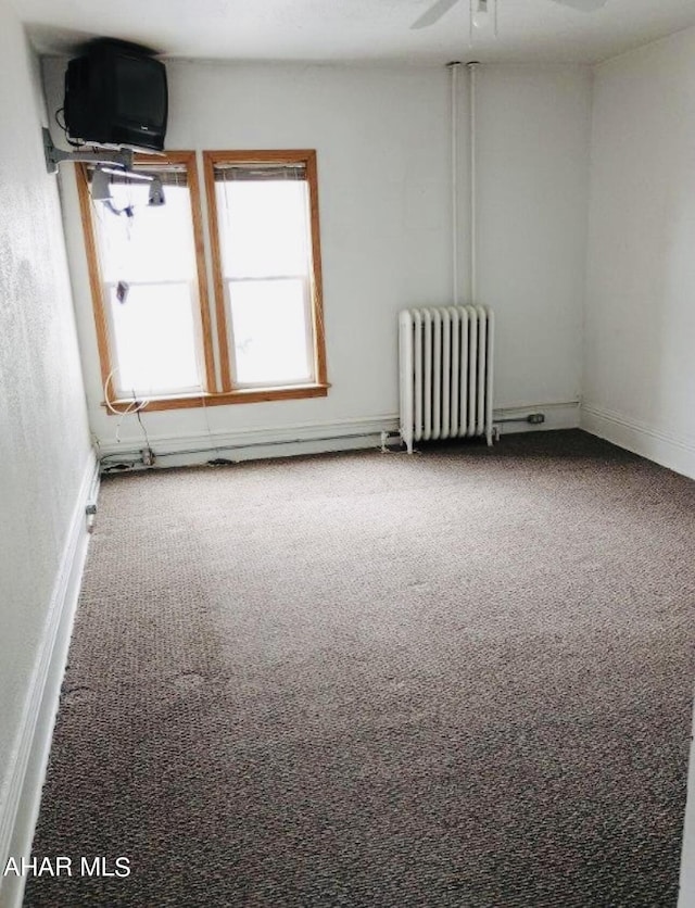 carpeted spare room featuring radiator heating unit and ceiling fan