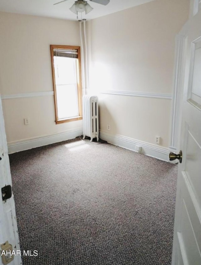 carpeted empty room featuring ceiling fan and radiator heating unit