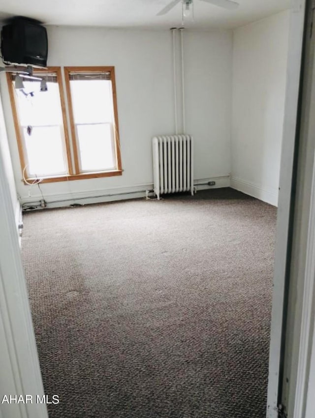 empty room featuring carpet, radiator, and ceiling fan