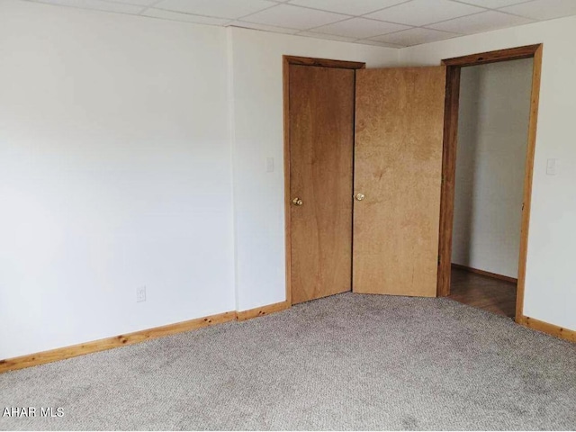 unfurnished bedroom featuring light carpet and a drop ceiling