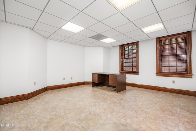 unfurnished room featuring a paneled ceiling and light tile patterned flooring