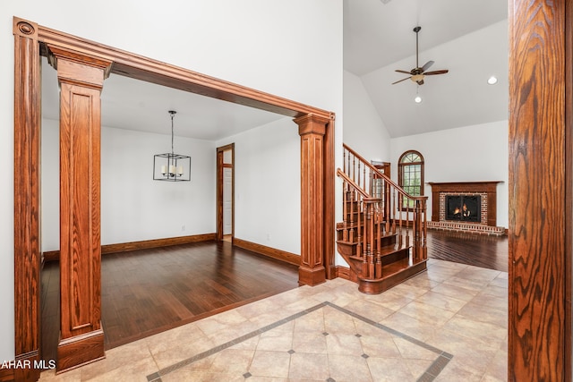 interior space featuring a chandelier, light hardwood / wood-style floors, high vaulted ceiling, and decorative columns