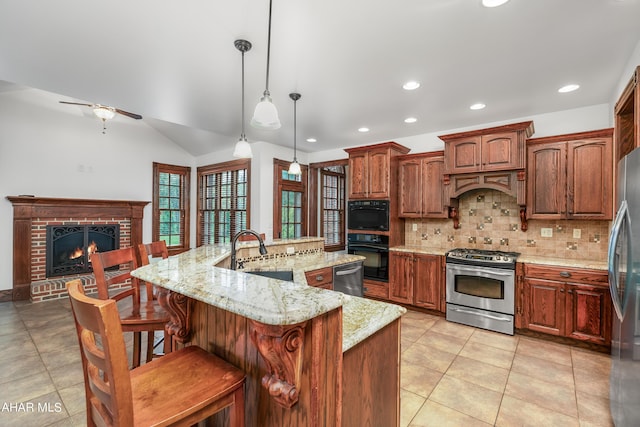 kitchen featuring a large island, sink, decorative light fixtures, a fireplace, and black appliances