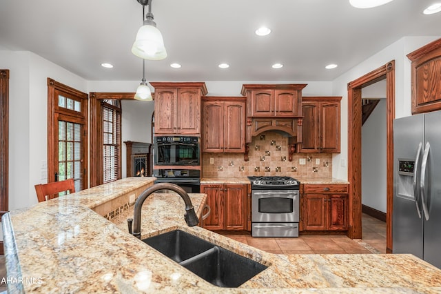 kitchen featuring black appliances, sink, hanging light fixtures, light tile patterned floors, and tasteful backsplash