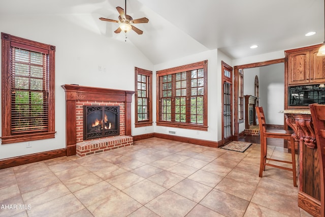 unfurnished living room with ceiling fan, a healthy amount of sunlight, lofted ceiling, and a fireplace