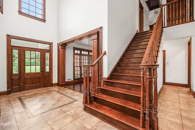 tiled entrance foyer featuring decorative columns and a high ceiling