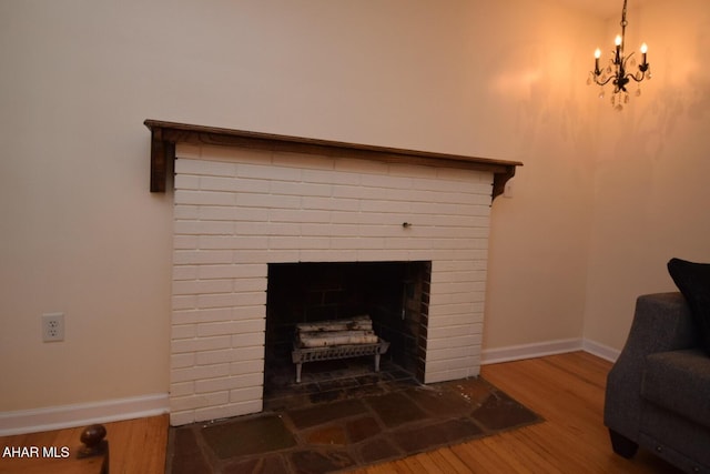 interior details with hardwood / wood-style flooring, an inviting chandelier, and a brick fireplace