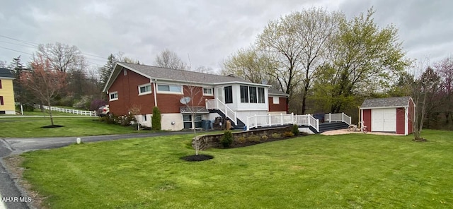 rear view of property with a wooden deck, a lawn, and a shed