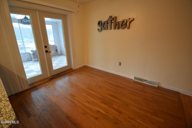 unfurnished room with hardwood / wood-style floors and french doors