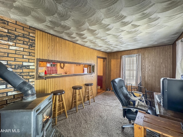 home office featuring a wood stove, dark carpet, and indoor bar