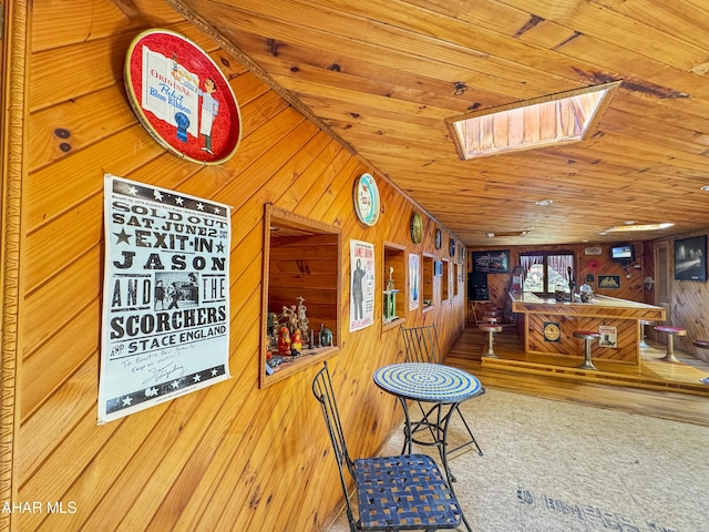 interior space featuring wooden ceiling, wooden walls, and vaulted ceiling with skylight