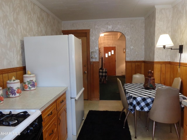 kitchen with white refrigerator, crown molding, and range with gas cooktop