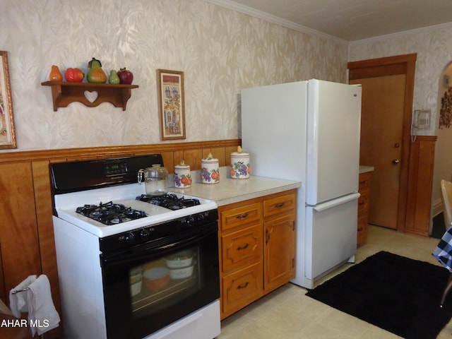 kitchen featuring crown molding, range with gas stovetop, and white fridge