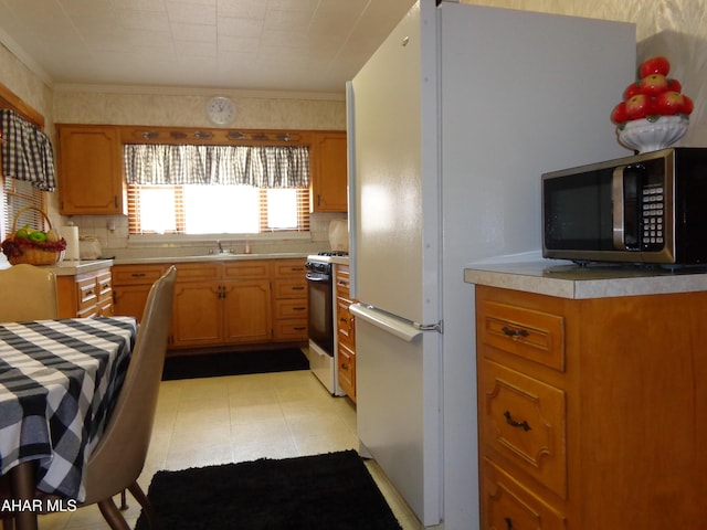 kitchen with ornamental molding, sink, white range with gas stovetop, and decorative backsplash