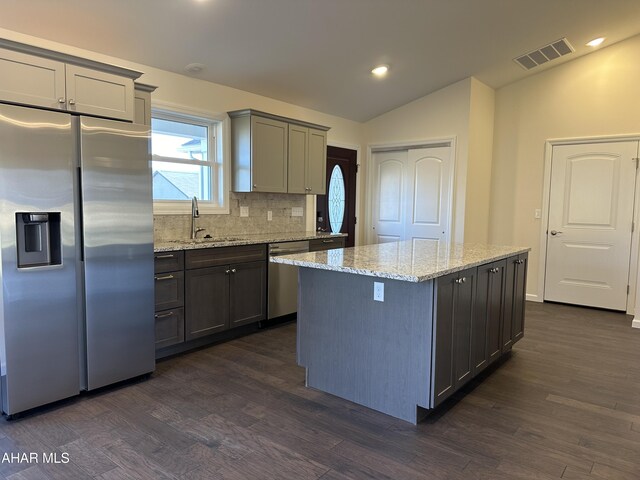 kitchen with sink, a center island, dark wood-type flooring, lofted ceiling, and appliances with stainless steel finishes