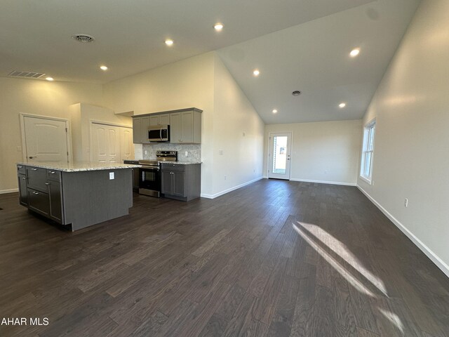 unfurnished room with plenty of natural light, dark hardwood / wood-style flooring, and vaulted ceiling