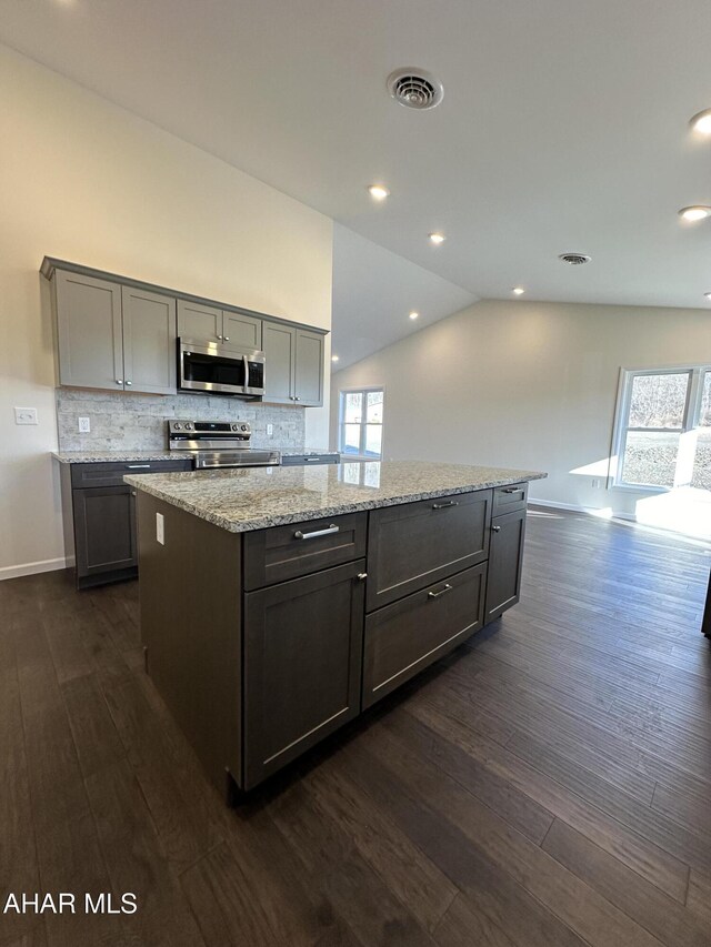 kitchen featuring a center island, dark hardwood / wood-style flooring, lofted ceiling, and stainless steel appliances