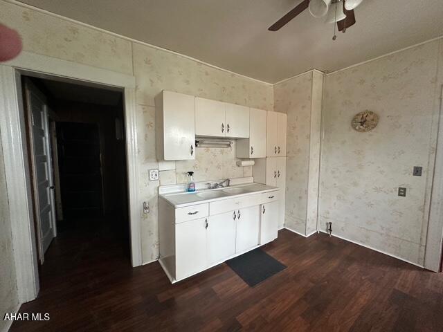 600 N 6th Ave, Altoona, PA 16601 - kitchen with dark wood-type flooring, light countertops, wallpapered walls, a ceiling fan, and white cabinetry