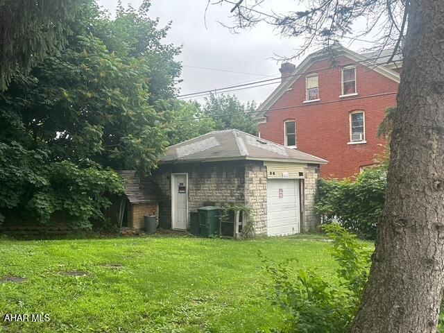 600 N 6th Ave, Altoona, PA 16601 - rear view of house with a lawn, a garage, stone siding, and a chimney