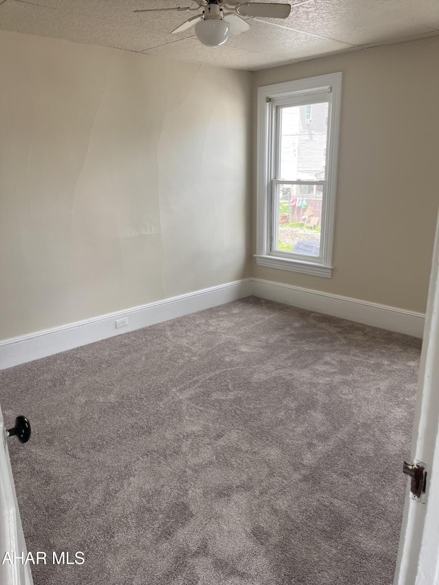 carpeted empty room featuring a ceiling fan and baseboards