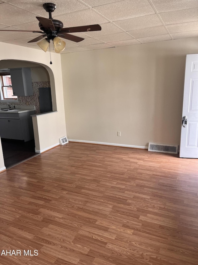 unfurnished living room with ceiling fan, wood finished floors, baseboards, and a sink