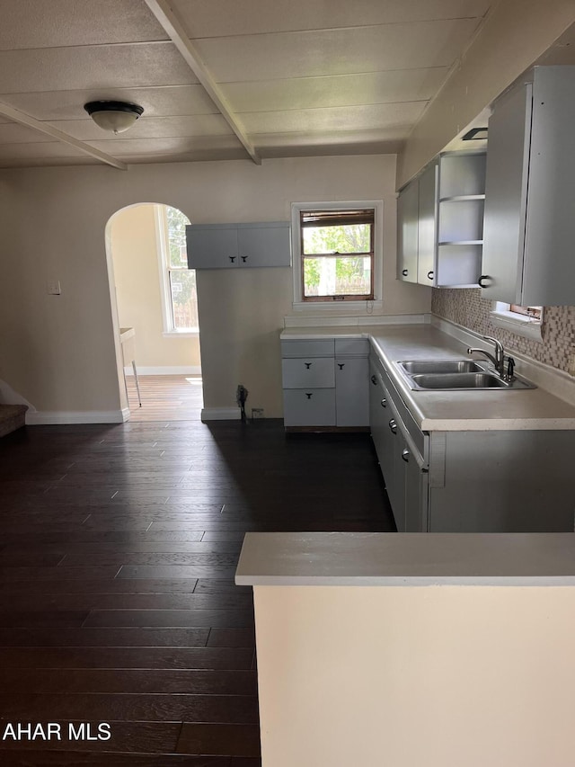 kitchen featuring arched walkways, open shelves, a sink, and plenty of natural light