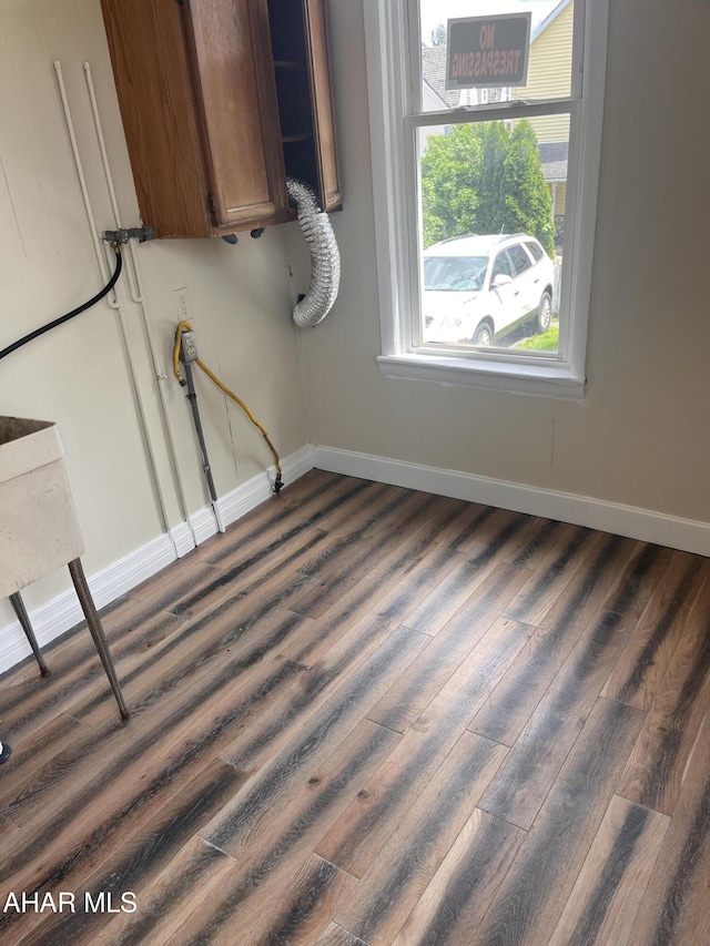 clothes washing area with dark wood finished floors and baseboards
