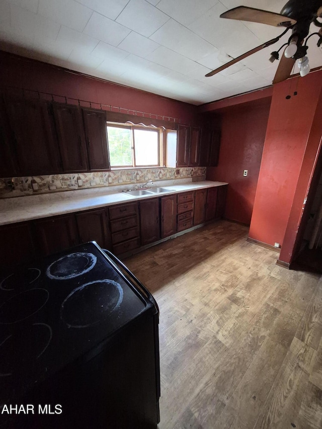 kitchen with ceiling fan, sink, tasteful backsplash, black electric range, and light hardwood / wood-style floors