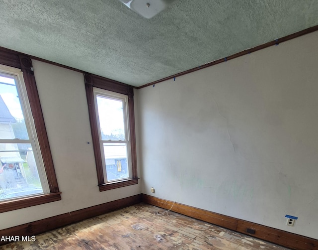 unfurnished room featuring a textured ceiling and light hardwood / wood-style flooring