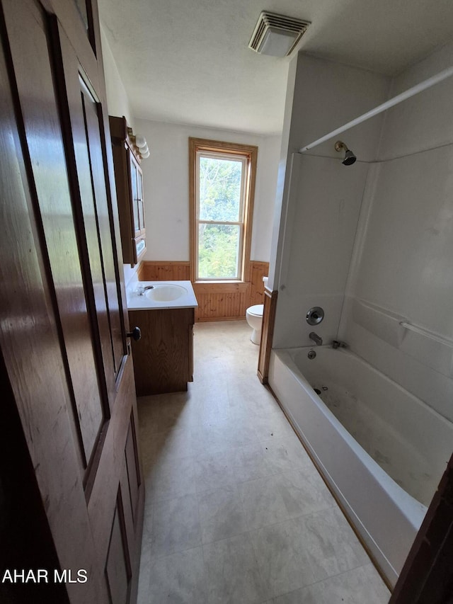 full bathroom with vanity, wood walls, toilet, and bathtub / shower combination