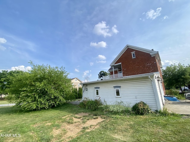 rear view of property featuring a balcony and a yard