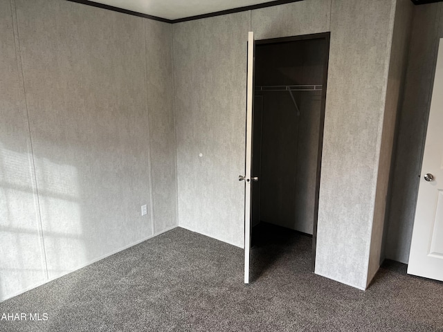 unfurnished bedroom featuring a closet and dark carpet