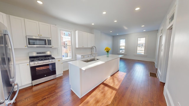 kitchen featuring an island with sink, appliances with stainless steel finishes, sink, and white cabinets