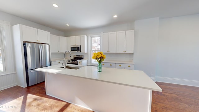 kitchen with dark wood-type flooring, sink, white cabinetry, a center island with sink, and appliances with stainless steel finishes