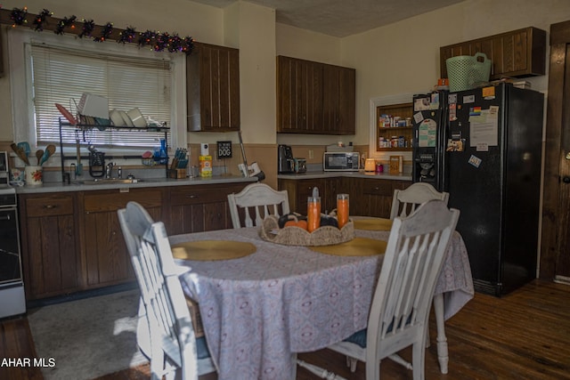 kitchen with a textured ceiling, black fridge, dark wood-type flooring, and sink