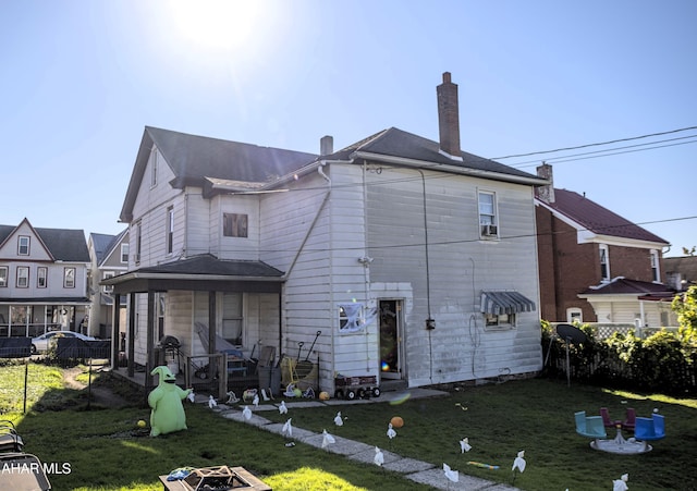 back of house with a yard and a fire pit