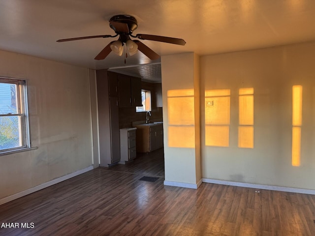 unfurnished living room featuring dark hardwood / wood-style floors, ceiling fan, and sink